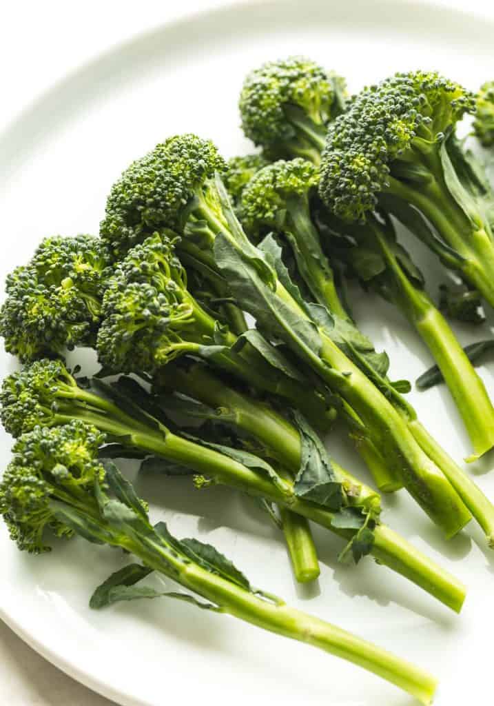 Stem broccoli broccolini plants with slender green stems, leafy foliage, and small green florets growing in a home vegetable garden.