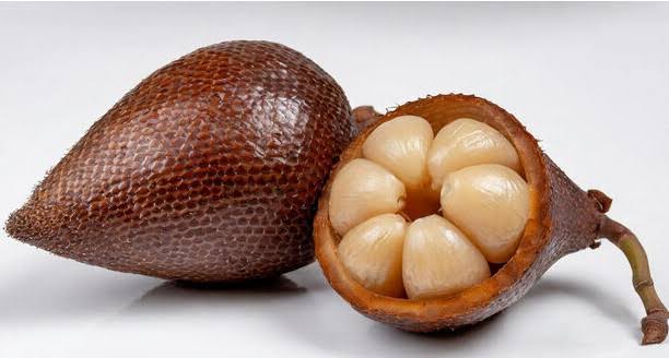 Salak fruit and salak palm showing reddish-brown scaly snake fruit, pale edible flesh, and long green tropical palm leaves.