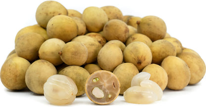 Fresh duku fruit seeds beside ripe pale-yellow duku fruits with translucent white flesh and glossy green leaves, showcasing a tropical evergreen fruit tree.