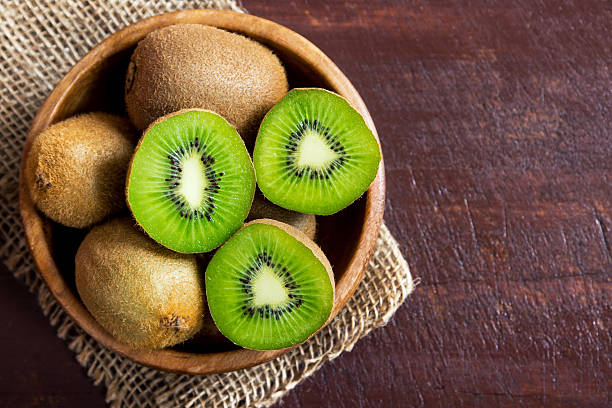 Kiwi fruit growing on a leafy climbing kiwi vine supported by a garden trellis