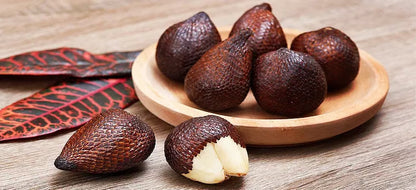 Salak fruit and salak palm showing reddish-brown scaly snake fruit, pale edible flesh, and long green tropical palm leaves.