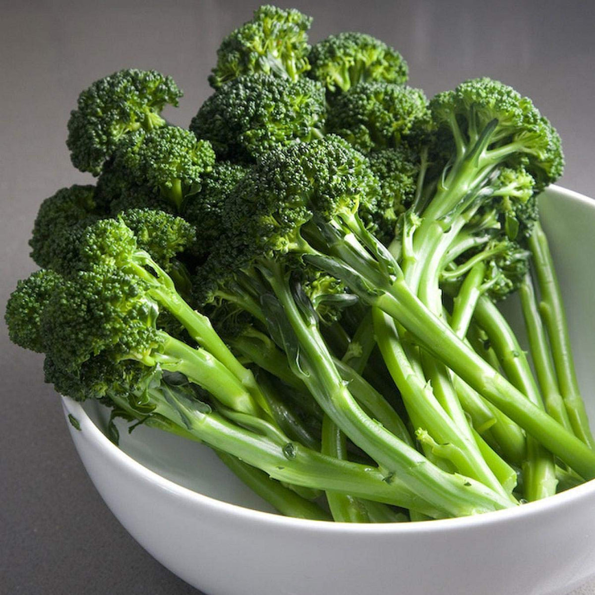 Stem broccoli broccolini plants with slender green stems, leafy foliage, and small green florets growing in a home vegetable garden.